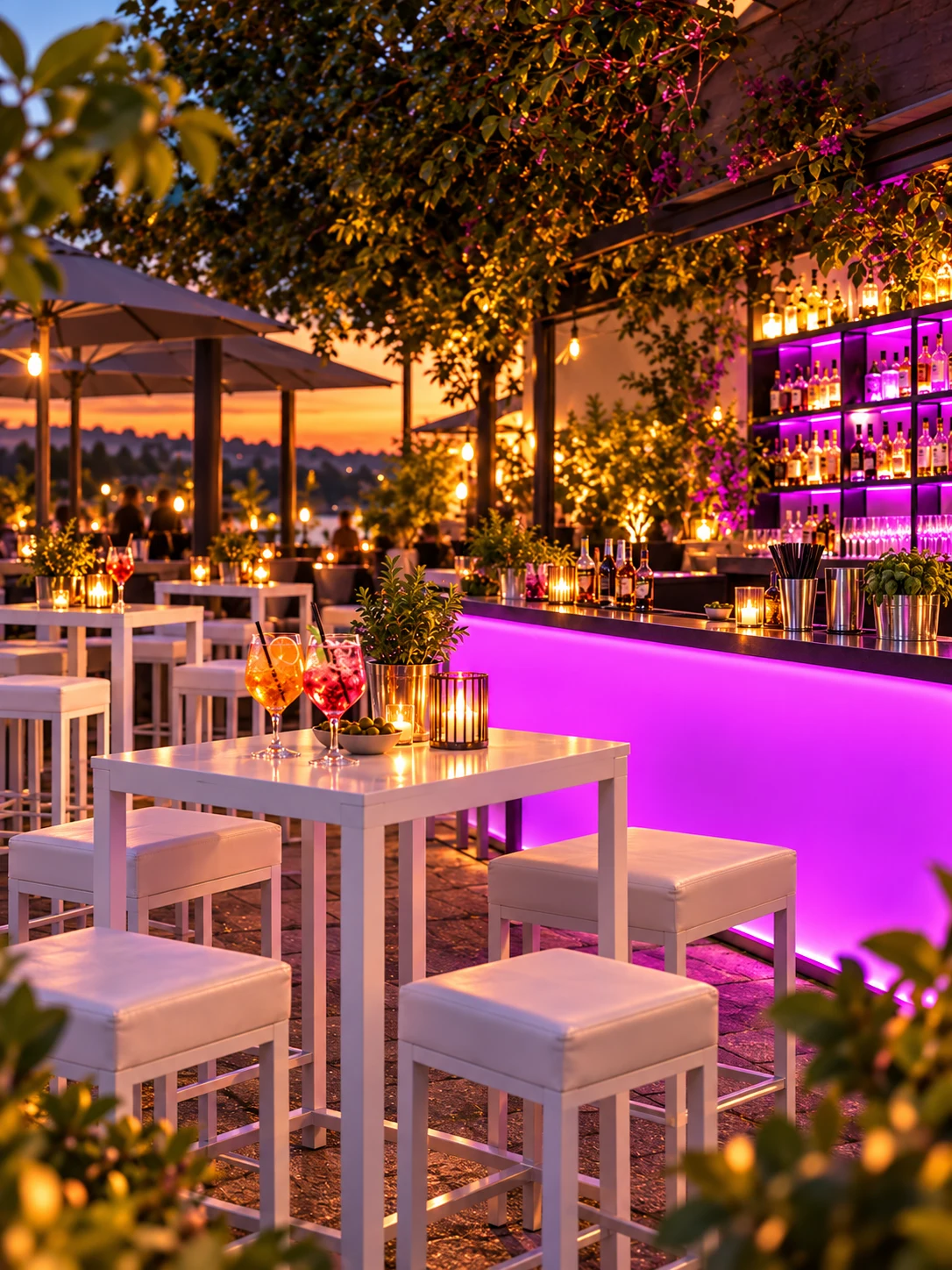 Stimmungsvolle beleuchtete Terrasse mit weißem Bartisch, weißen Hockern und Drinks